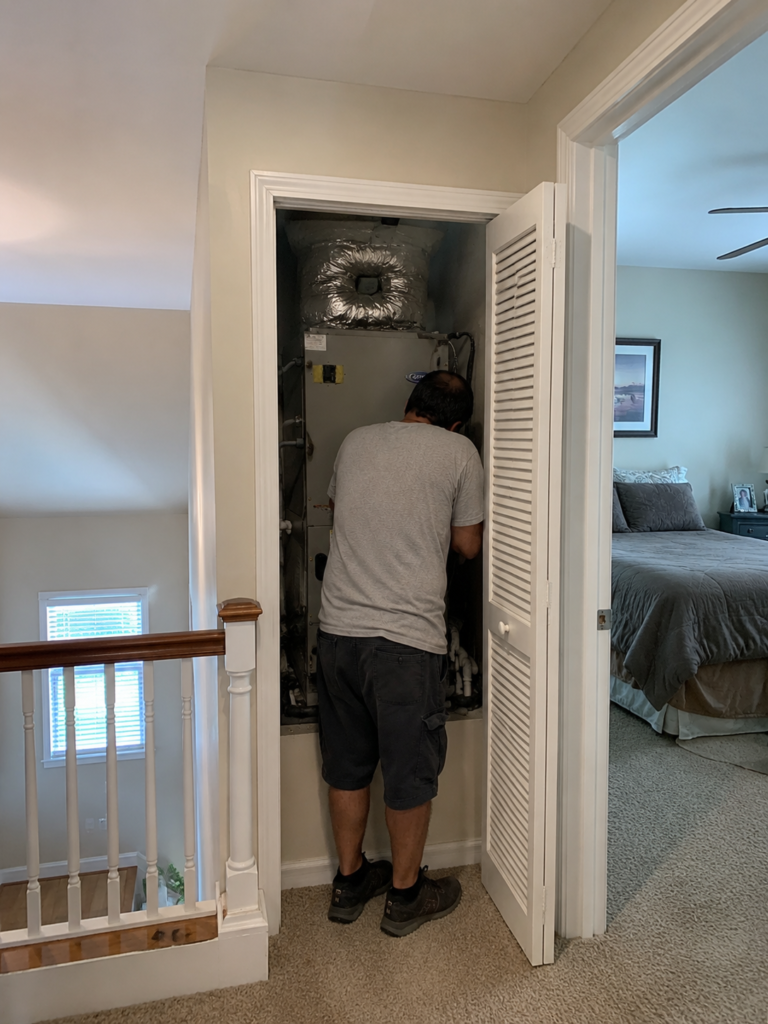 HVAC technician checking a residential AC system for upstairs cooling problems