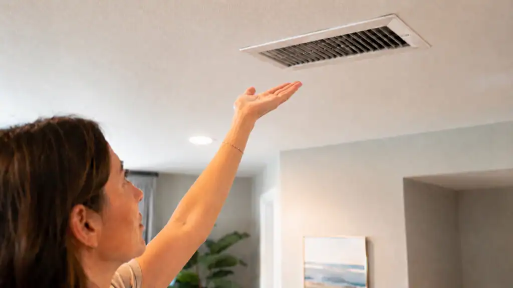 Homeowner checking airflow from an AC vent in an Oviedo home